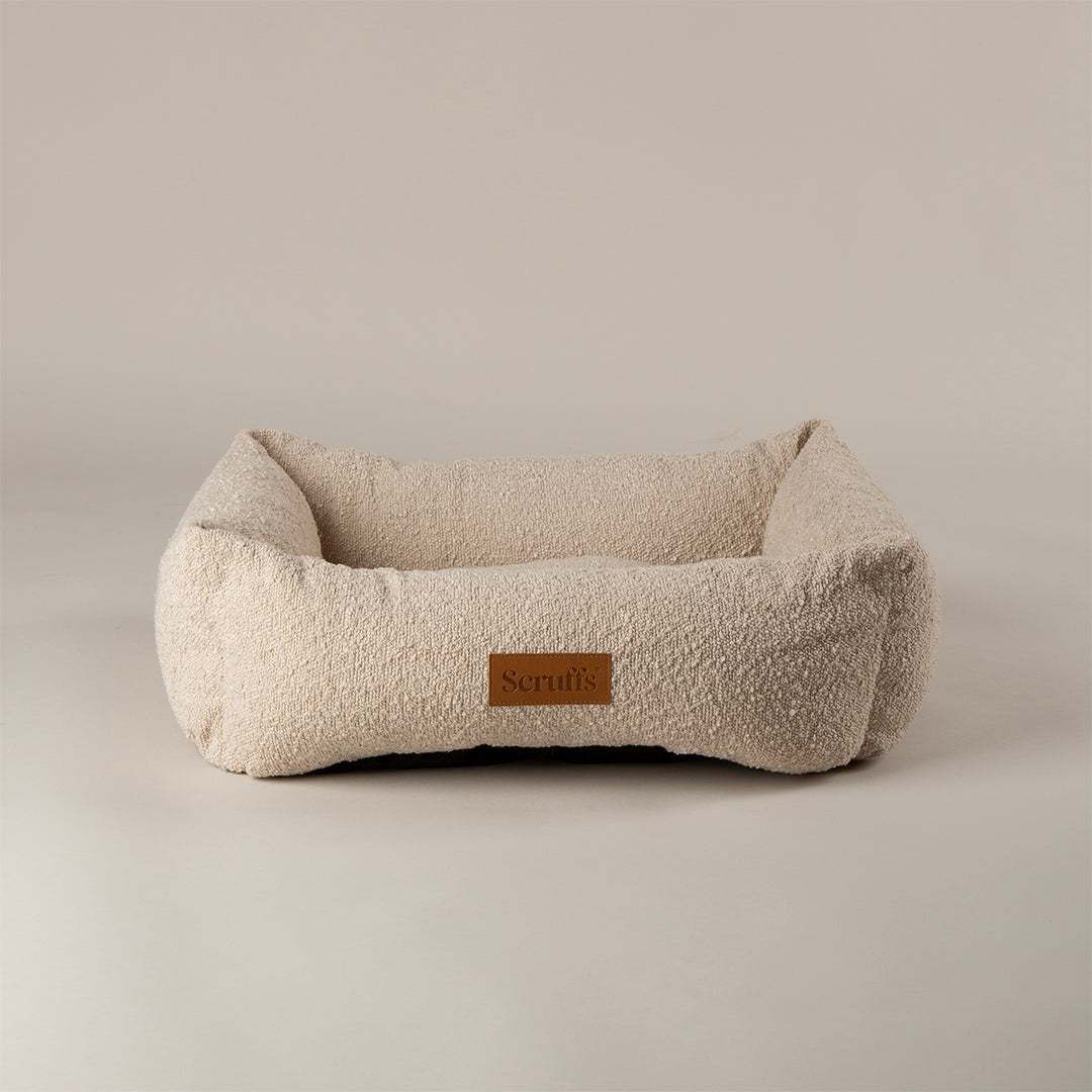 Beige dog bed with a brown label on a beige background