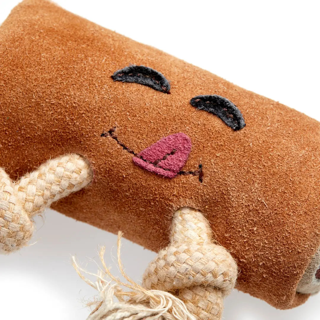 A close up of brown eco dog toy resembling a chocolate bar with a smiling face and jute rope legs.