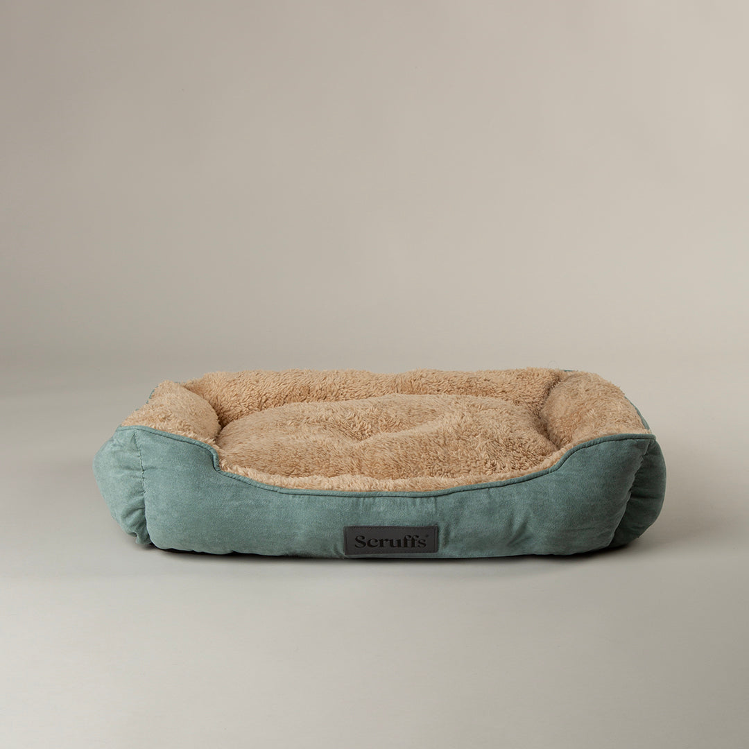 Green soft dog bed with teal exterior and beige interior on a plain background