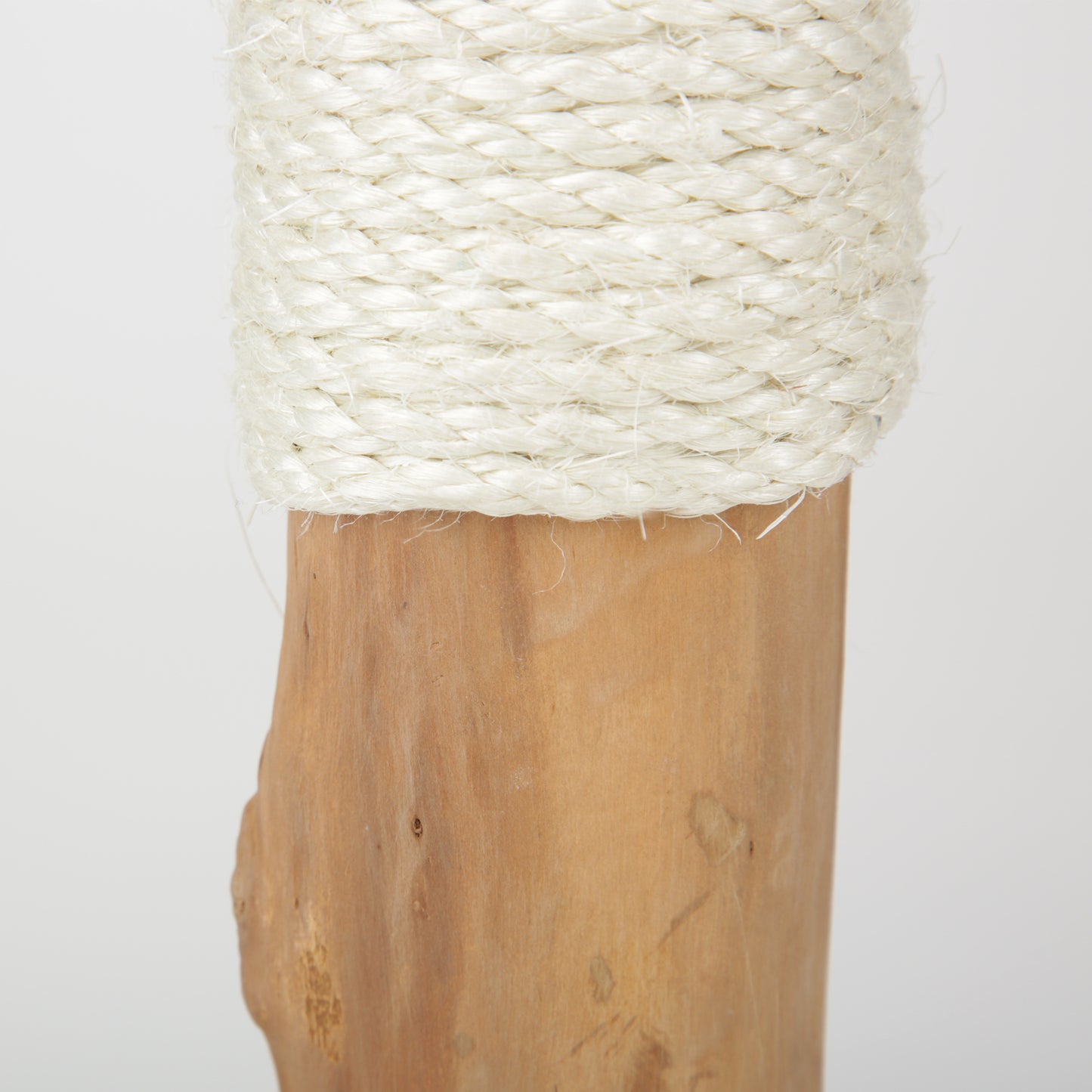 Wooden cat scratching post with a coiled white rope on a plain background