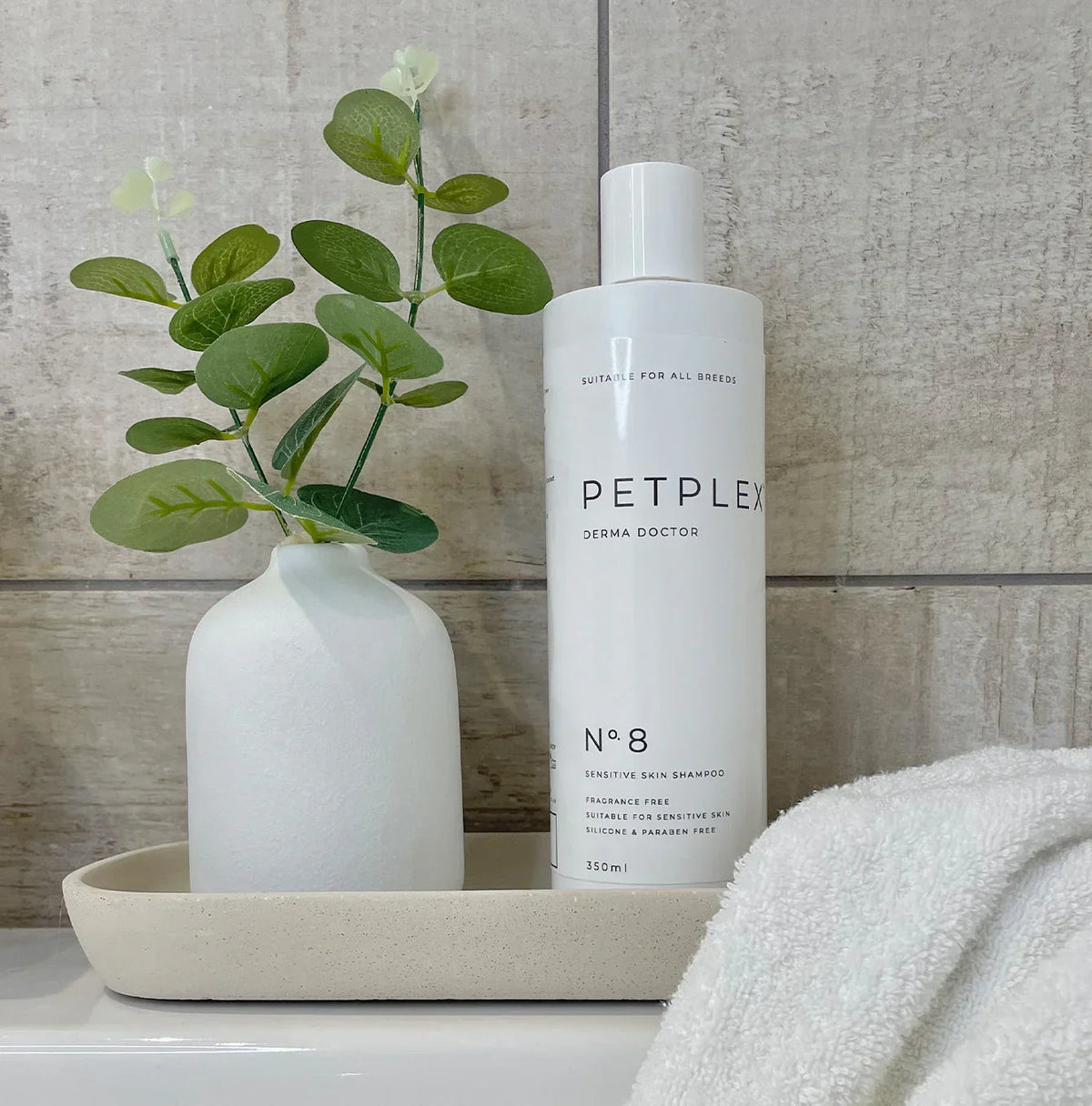 PetPlex No. 8 Derma Doctor Sensitive Skin Dog Shampoo displayed on a bathroom tray with a towel and decorative vase