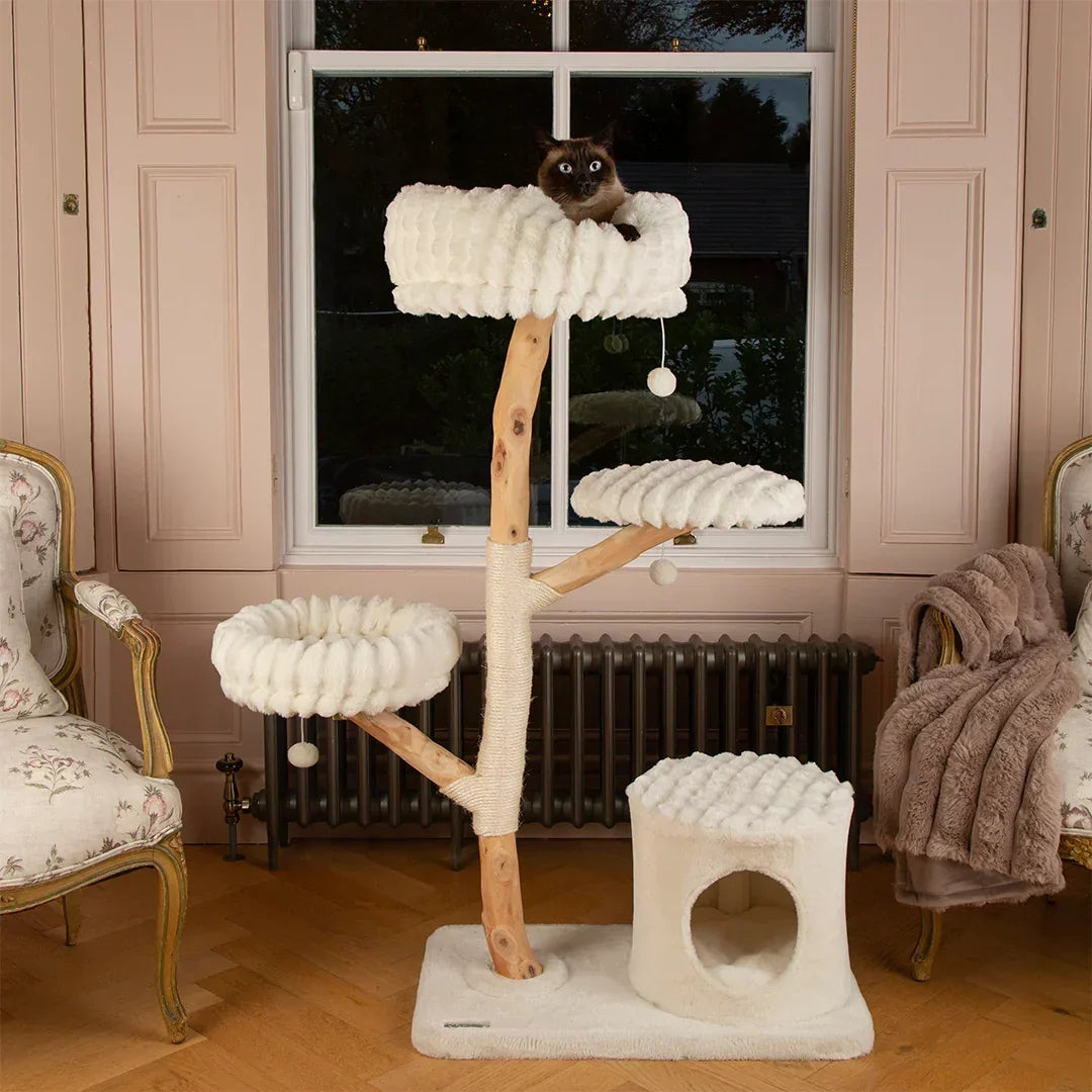 Scruffs Alpine Pyrenees Cat Tree in Cream placed beside a window in a living room with elevated resting platforms